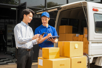 Asian man signs for parcel delivery, confirming shipment. Concept of e-commerce, logistics, and fast courier service for secure package handling.