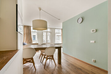 Bright and airy dining area featuring minimalistic design, wooden flooring, and large windows that invite natural light, creating a welcoming atmosphere.