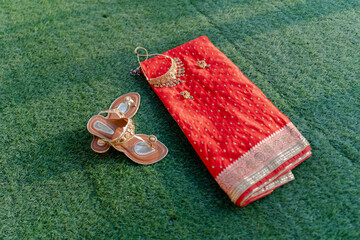 Beautiful red bridal saree with intricate golden embroidery, paired with traditional jewelry and embellished sandals, symbolizing Indian wedding elegance.