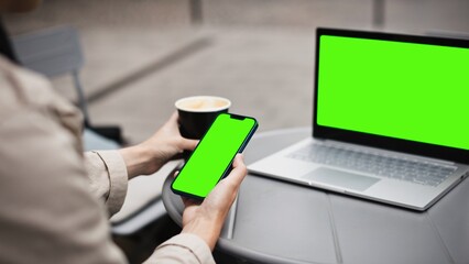 View of Caucasian woman sitting at table in front of laptop with green screen. In meantime using...