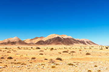 Typical lifeless landscape of Namibia, Africa. Sapless desert and mountains on clear blue sky background