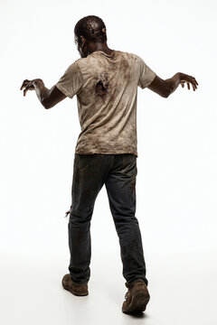 Rear back view of a Black African American Male zombie in a attack action pose reaching out. Isolated white studio background.