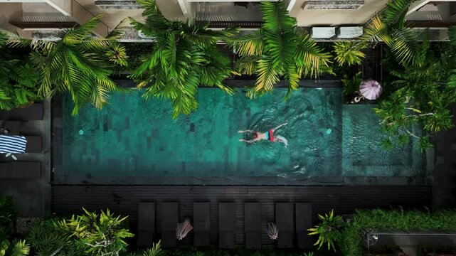 Aerial view of Active man,  swimming in pool, drone view from above, Bali villa, tropical vacation, holiday on island hotel resort