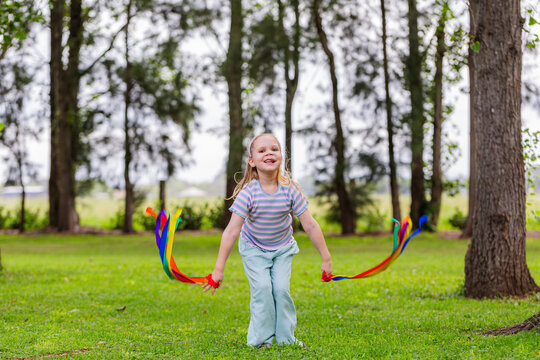 Girl with rainbow streamers running around outside in country