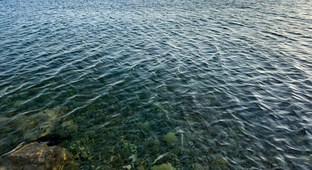 clear shallow sea water with visible stones and gentle ripples. natural aquatic texture. eco concept. wellness design themes
