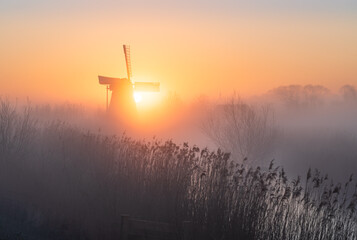 Dawn at a traditional, Dutch windmill in the spring fog.