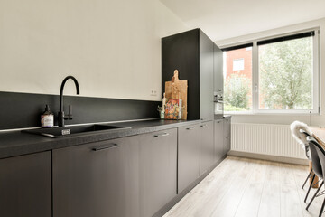 A sleek and contemporary kitchen featuring minimalist cabinetry, a stylish sink, and large windows that provide ample natural light.