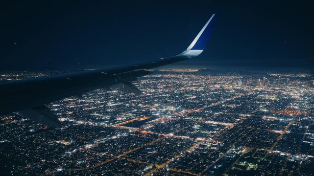 The breathtaking view from an airplane window at night displays the sparkling city lights just moments before the plane descends for landing