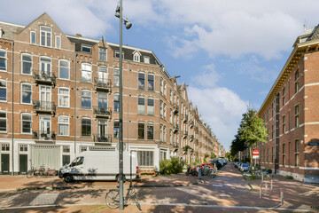 Naklejka premium A scenic view of charming brick buildings lining a serene urban street, showcasing classic European architecture under a clear blue sky.