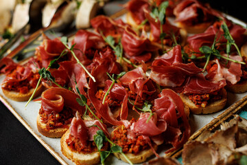 A tray of meat and vegetables with a green garnish. The meat is sliced and arranged on a white plate