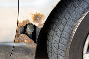 A hole in the rusted body of a car.