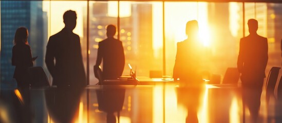 Blurred silhouettes of business people in an office meeting room with sunlight shining through the windows