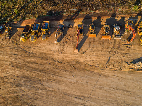 Machinery on worksite lined up in morning light ready to continue construction on bypass road
