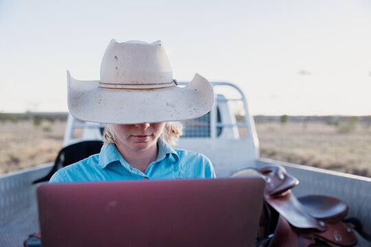 Female looking at computer outdoors with vehicle in background