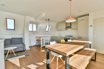 A stylish, modern kitchen with a dining area featuring minimalist furniture and natural light from large windows, creating an inviting atmosphere.