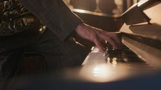 Closeup of unrecognizable musician hand playing piano during jazz performance under warm, ambient lighting