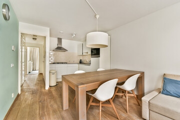 A bright, modern kitchen and dining space featuring wooden flooring, a sleek dining table, and contemporary furnishings under soft lighting.