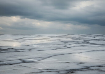 Obraz premium Aerial view of cracked ice landscape under a cloudy sky, abstract textures and natural environment