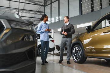 A consultant at a car dealership helps a customer choose a new car