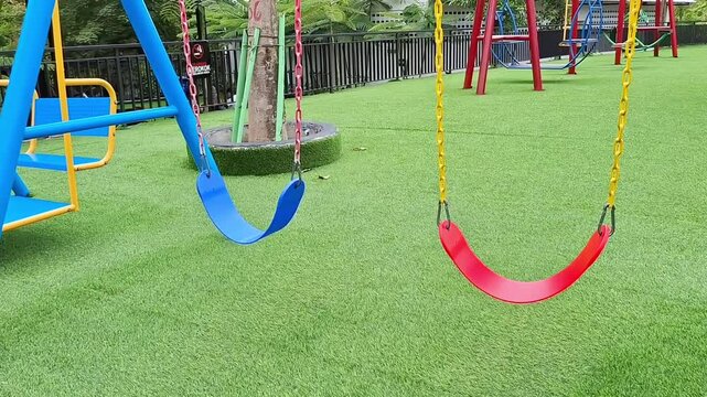 Empty Playground Swings: Blue and Red on Artificial Turf
