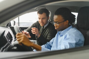 A consultant at a car dealership helps a customer choose a new car.