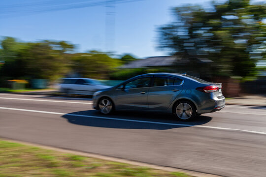 Panning shot of car vehicle traveling along highway through town