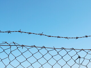 A weathered wire mesh fence with barbed wire secures an unused pasture, creating a clear boundary...
