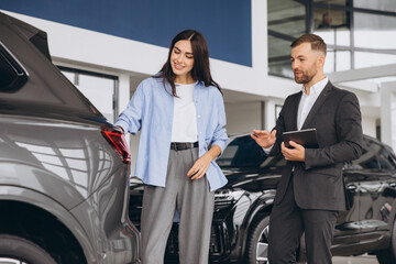 Young woman customer female buyer client wears shirt consult with salesman hold tablet choosing...