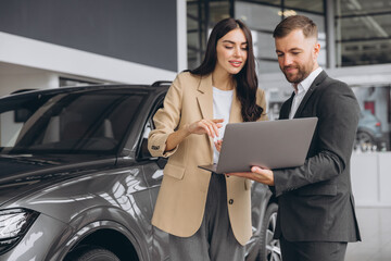 Male car salesman, recommends a car to a woman buyer, inspects cars in the showroom, the seller...