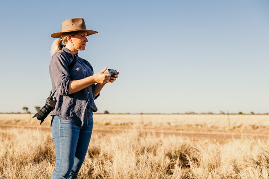 Woman photographer looking forward while holding drone controller
