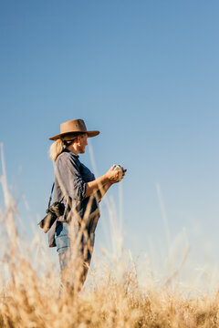 Female with camera over shoulder flying a drone looking to the sky