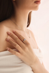 Fototapeta premium Cropped side view portrait of woman with engagement ring and silver necklace, radiating soft beauty and romantic charm through delicate accessories. Concept of jewelry, luxury, accessories.