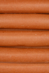 A close-up of several smooth, light brown cooked chicken frankfurters stacked closely together