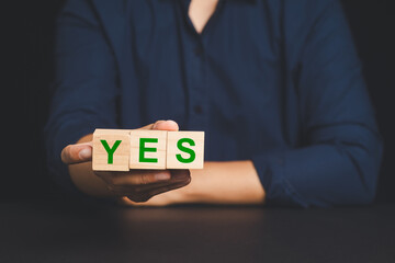 Hand showing YES text on wood cubes symbolizing agreement, confirmation, or positive choice.