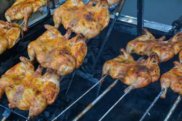 Chicken on the fire. Chicken BBQ. Roasted chicken in the oven in a restaurant, closeup of photo. Grilled chicken on the spit in the smoke. Fast food
