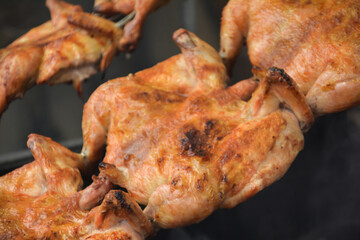 Chicken on the fire. Chicken BBQ. Roasted chicken in the oven in a restaurant, closeup of photo. Grilled chicken on the spit in the smoke. Fast food