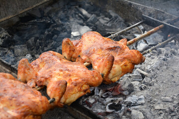 Chicken on the fire. Chicken BBQ. Roasted chicken in the oven in a restaurant, closeup of photo. Grilled chicken on the spit in the smoke. Fast food