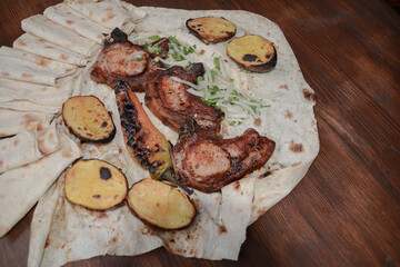 Grilled meat. Pork barbecue. Fried meat with onions, potatoes wrapped in pita bread. Lamb steak on pita bread with grilled potatoes on wooden table. Restaurant food. Fast food