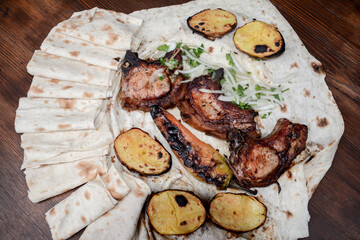 Grilled meat. Pork barbecue. Fried meat with onions, potatoes wrapped in pita bread. Lamb steak on pita bread with grilled potatoes on wooden table. Restaurant food. Fast food