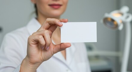 A woman holds a blank business card.