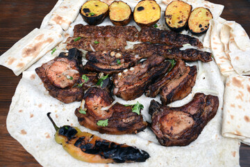 Barbecue with grilled meat and shish kebab. Grilled lamb ribs, kebab, potatoes and pita bread on wooden board. Restaurant food, pork barbecue, bbq.