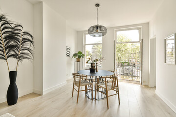 A stylish modern dining area featuring a round table surrounded by elegant chairs. The space is bright with natural light and decorative plants.