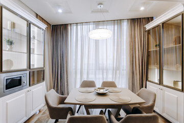 A dining room with a table and chairs by a large window