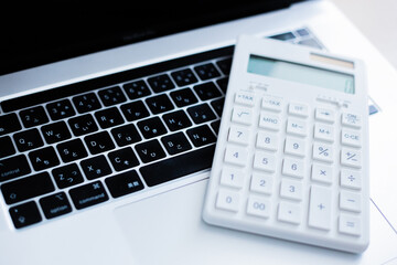 ノートパソコンと電卓で行うビジネス計算のイメージ