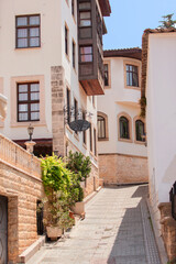 A narrow old street with a stone wall on the side. The street is lined with houses and has a stone path.
