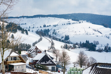 Snow-covered village nestled in serene hills during a peaceful winter afternoon, showcasing the beauty of nature in a tranquil setting
