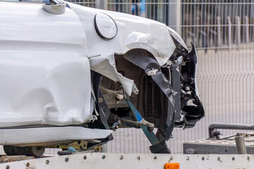 A car with a seriously damaged front after a road collision. The car is on a tow truck. The damage...
