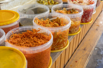 A market stall with variety of pickled vegetables, Korean soy asparagus, shredded Korean carrots stored in transparent plastic containers. Selective focus