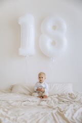 Little cute boy with white balloons celebrating 18 months.