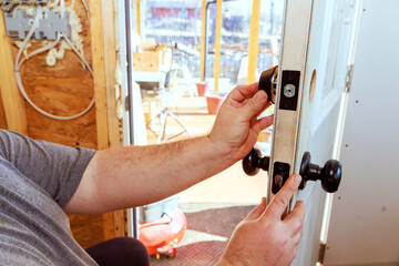 Contractor is carefully installing door lock at works, secure fit during construction